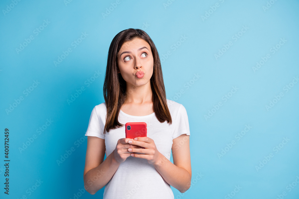 Photo of young pretty lovely cute attractive girl pout lips look copyspace use smartphone isolated on blue color background Photo of young pretty lovely cute attractive girl pout lips look copyspace use smartphone isolated on blue color background