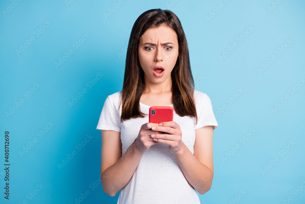 Photo of impressed unhappy young lady wear white clothes texting modern gadget isolated blue color background Photo of impressed unhappy young lady wear white clothes texting modern gadget isolated blue color background