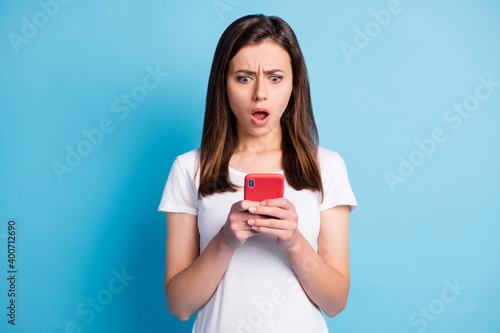 Photo of impressed unhappy young lady wear white clothes texting modern gadget isolated blue color background