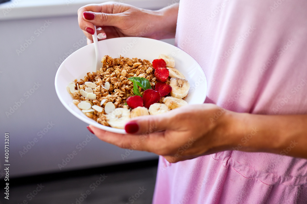 Woman eating healthy breakfast bowl, hold in hand Woman eating healthy breakfast bowl, hold in hand