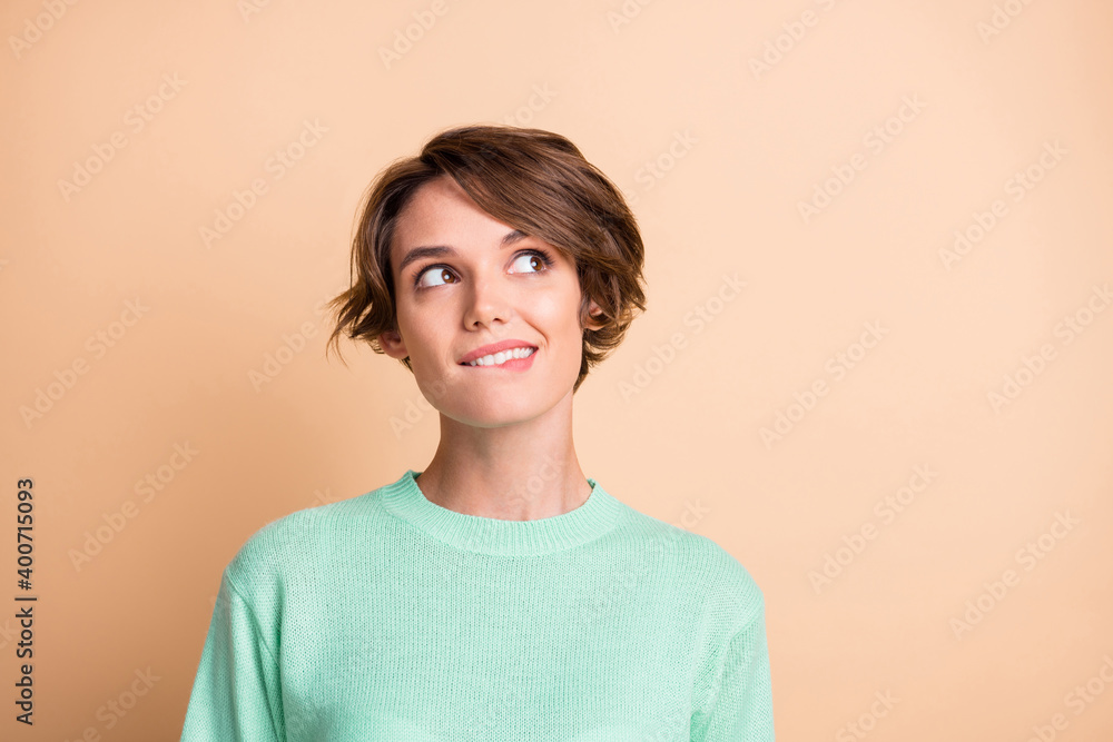 Portrait of young attractive smiling girl bite lips look copyspace dreaming thinking isolated on beige color background Portrait of young attractive smiling girl bite lips look copyspace dreaming thinking isolated on beige color background