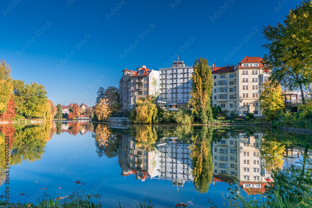 Park at the shore of Lake Lietzen with buildings reflecting in the water in Berlin, Germany