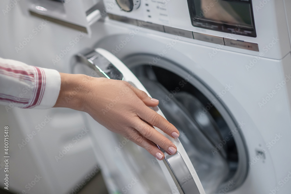 Close up picture of womans hands examining a washing machine Close up picture of womans hands examining a washing machine