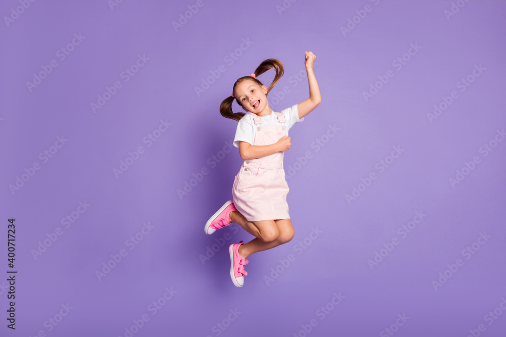 Full size photo of charming happy little girl jump up air weekend positive isolated on purple color background Full size photo of charming happy little girl jump up air weekend positive isolated on purple color background
