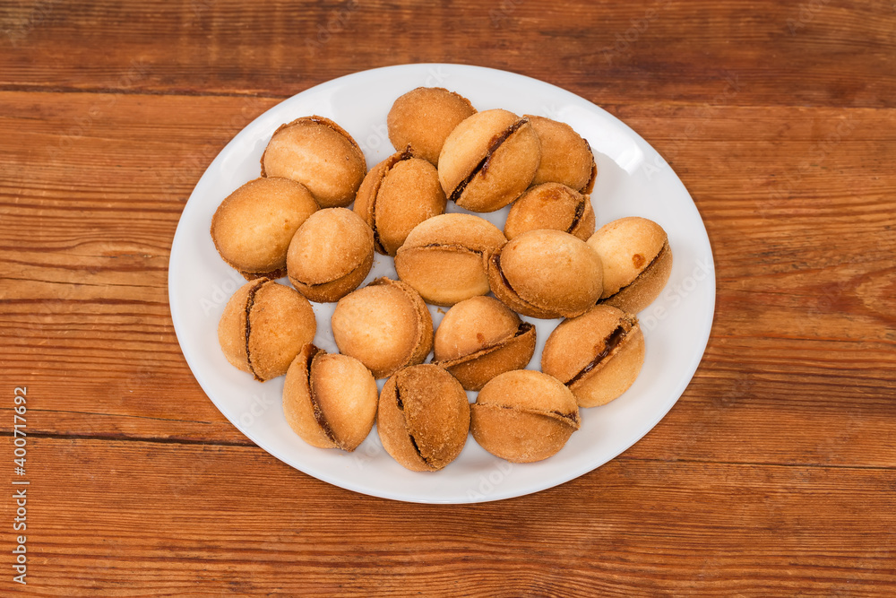 Cookies in shape of nuts with caramel filling on dish Cookies in shape of nuts with caramel filling on dish