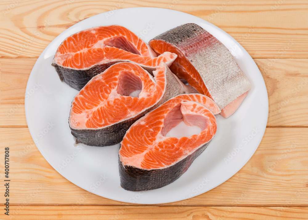 Pieces of uncooked rainbow trout on dish on rustic table Pieces of uncooked rainbow trout on dish on rustic table