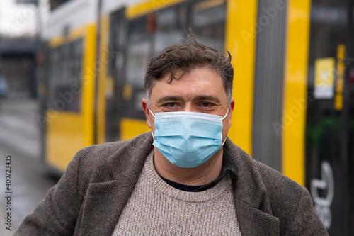 Wearing protective masks waiting for the streetcar. Disease outbreak, coronavirus covid-19 pandemic. Man covering his face with a medical mask to protect his nose and mouth