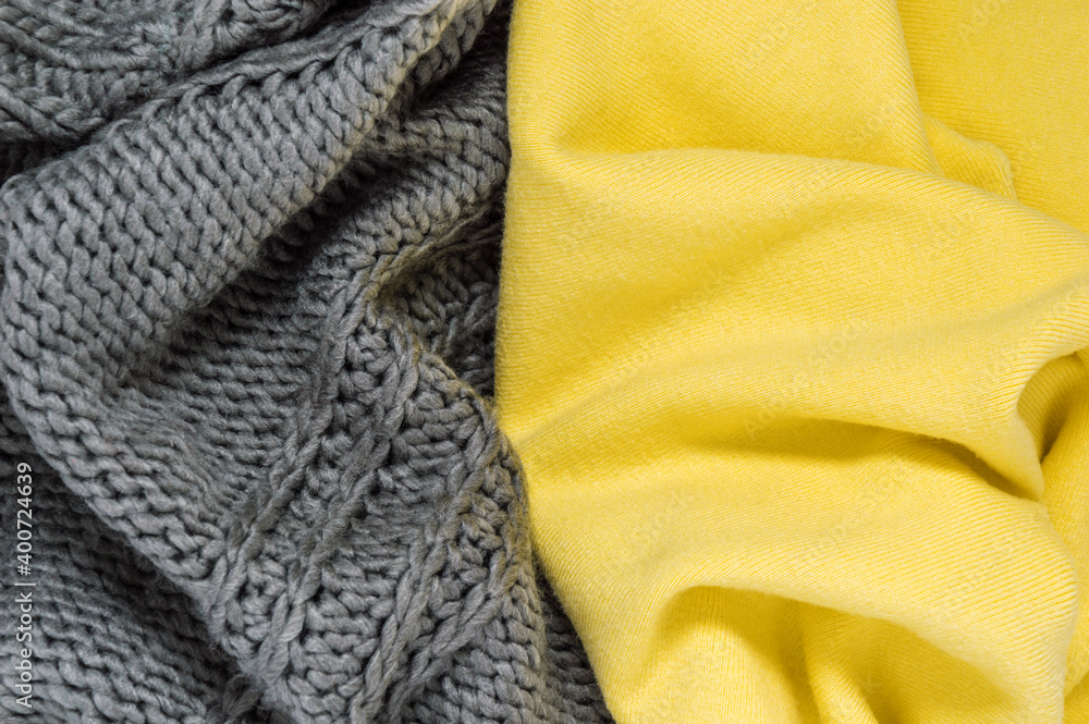 Fototapeta premium Knitted sweater or scarf as wool texture in trendy colors of year 2021 illuminating yellow and ultimate gray. Vivid textile background with fashionable winter clothes or accessories and copy space