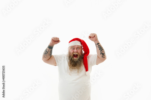 Isolated portrait on a white background of an overweigh man in Santa Claus hat expressing success, victory an goal achievement photo