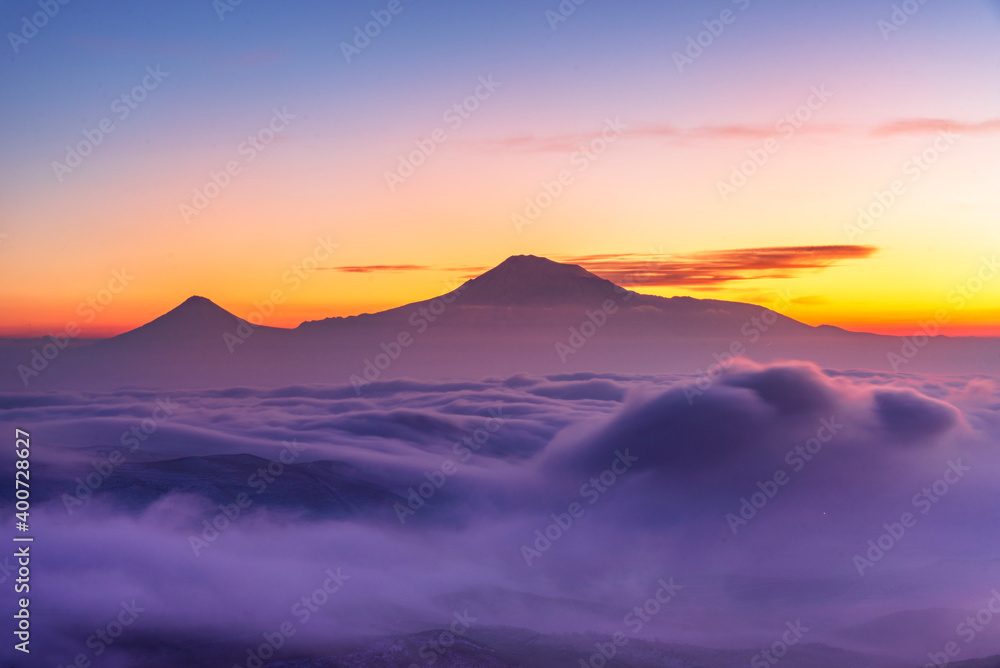 Beautiful sunset with long exposure clouds. The mountains in a clouds and fog.
