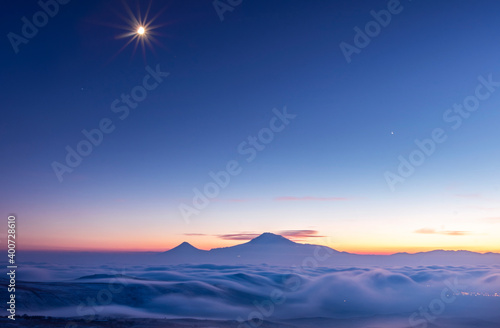 Beautiful after sunset with long exposure clouds. The mountains under starry blue sky and moon in clouds and fog.