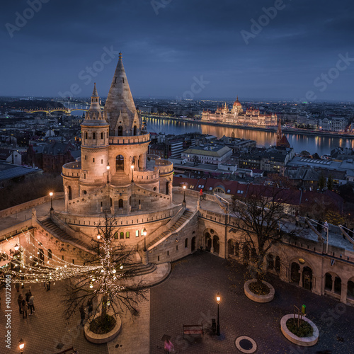 Budapest, Hungary - Aerial view of the famous illuminated Fisherman's Bastion (Halaszbastya) with Parliament of Hungary and festive lights at blue hour on a calm christmas night