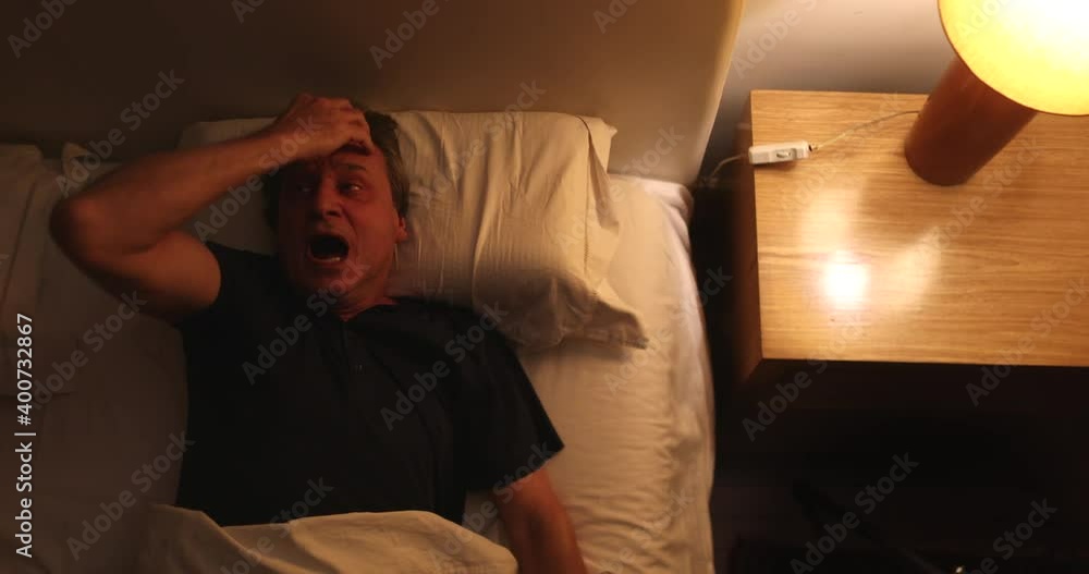 Person waking up at night, turning bedside light ON, man stretching and getting up from bed Person waking up at night, turning bedside light ON, man stretching and getting up from bed