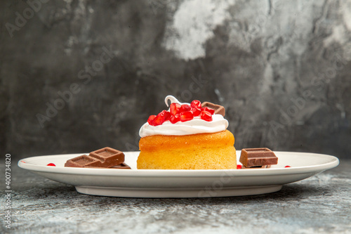 front view berry cake and chocolates on white oval plate on grey-white isolated background with free space photo