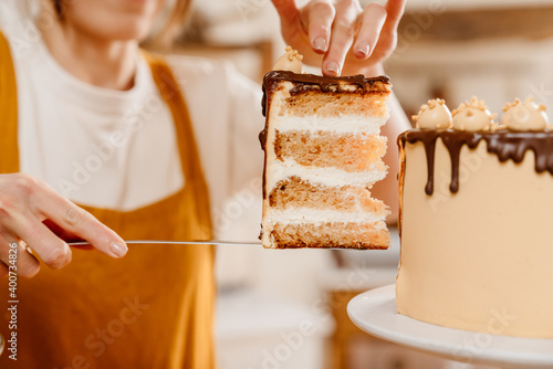 Caucasian pastry chef woman showing piece of cake with chocolate cream photo