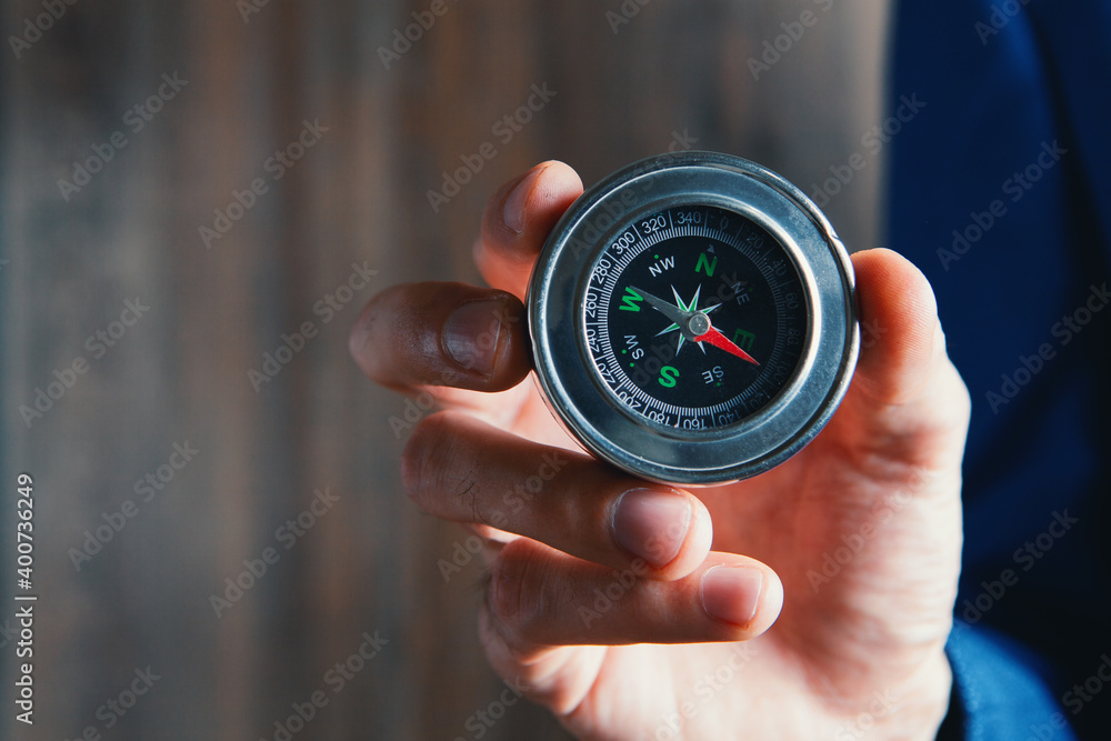businessman holds a metal compass in his hands. businessman holds a metal compass in his hands.