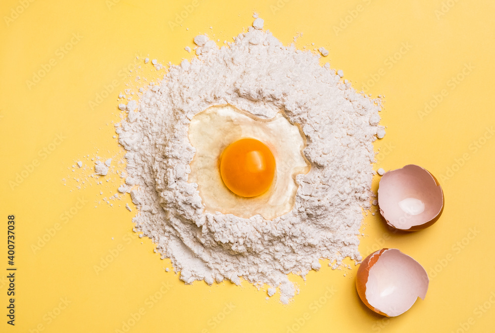 Broken egg yolk on flour for the dough on yellow background. Baking concept. Broken egg yolk on flour for the dough on yellow background. Baking concept.