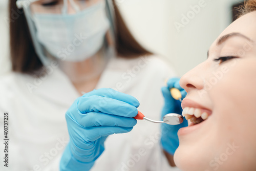 Doctor in white coat performing dental treatment on a smiling client