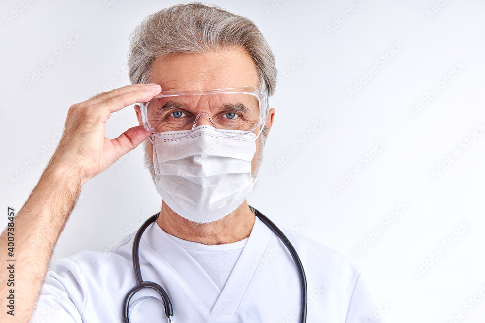 doctor man wearing protective eyeglasses for preparing for work, elderly male in white medical suit looks at camera isolated on white background doctor man wearing protective eyeglasses for preparing for work, elderly male in white medical suit looks at camera isolated on white background