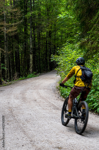 Fototapeta Naklejka Na Ścianę i Meble -  Young Man On Mountainbike Drives On Gravel Road Through Forest