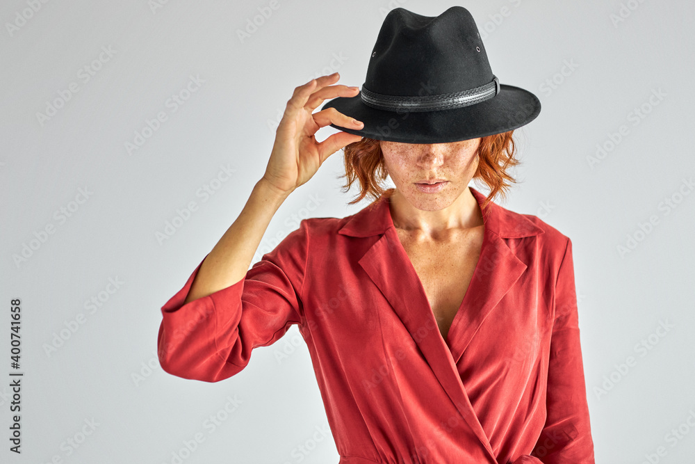 woman with short natural red haired in elegant black hat looking down, having charming appearance and personality woman with short natural red haired in elegant black hat looking down, having charming appearance and personality
