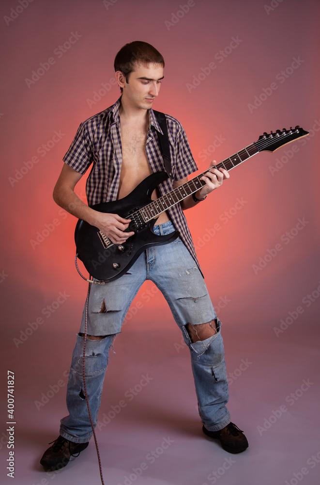 Young guitarist play music on his electric guitar with bright emotions. 