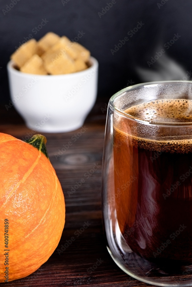 A cup of black coffee on wooden table. A glass mug of coffee. Pumpkin and cane sugar on a wooden background. Morning coffee A cup of black coffee on wooden table. A glass mug of coffee. Pumpkin and cane sugar on a wooden background. Morning coffee