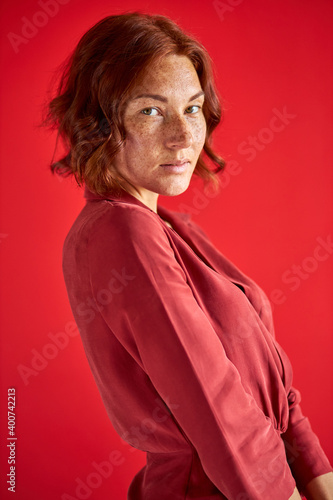 woman in dress lookng at camera, short haired female isolated over red background