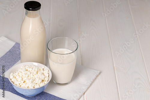 Cup of milk and cottage cheese in bowl on table