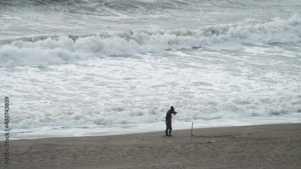 Fisherman fishing on the stormy ocean coast in 4k slow motion 60fps Fisherman fishing on the stormy ocean coast in 4k slow motion 60fps