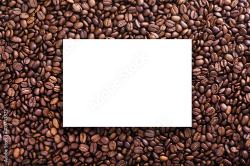 Roasted beans background with coffee grains, white epmty board