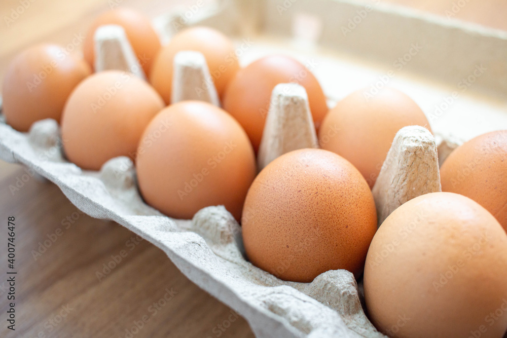 Closeup brown egg in a cardboard box from a supermarket on a wooden floor. Closeup brown egg in a cardboard box from a supermarket on a wooden floor.