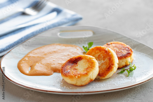 Russian cheesecakes served on plate with sauce