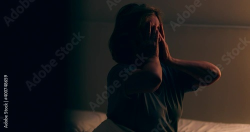 Senior woman getting up from bed at night. Tired person waking up at dawn