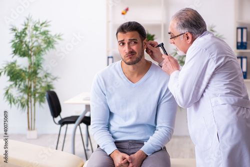 Young sick man visiting old doctor otolaryngologist