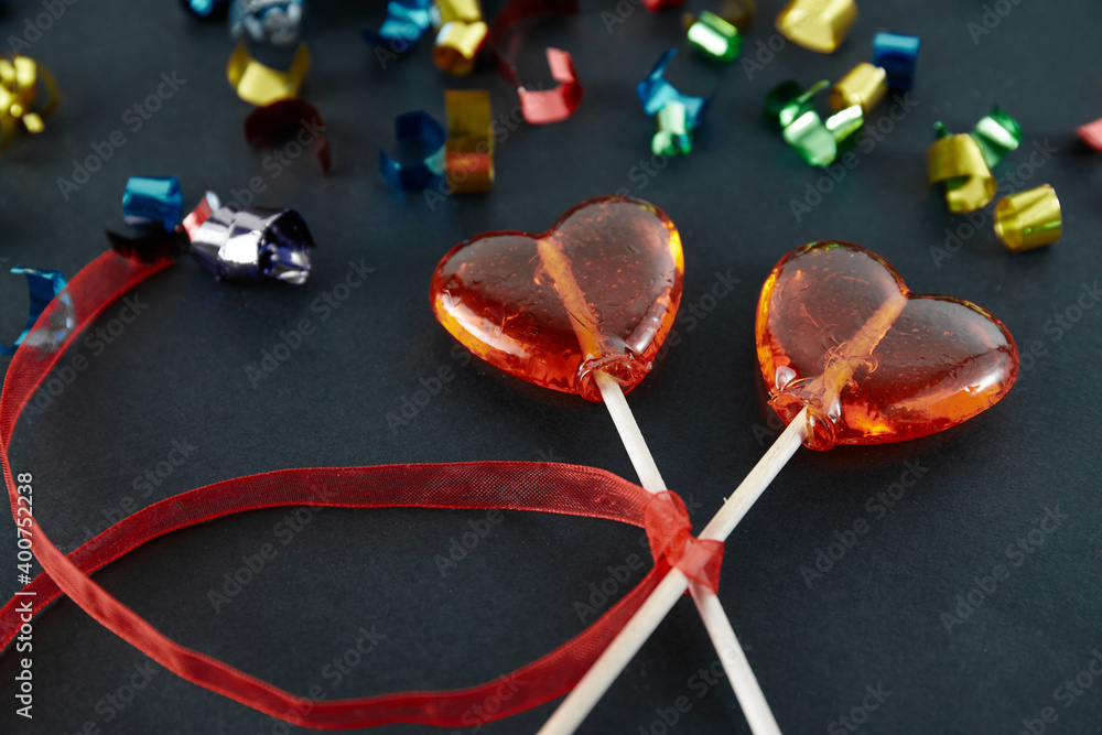 Heart-shaped sweets on a stick. Valentine's Day. Background. Candy on black background Heart-shaped sweets on a stick. Valentine's Day. Background. Candy on black background