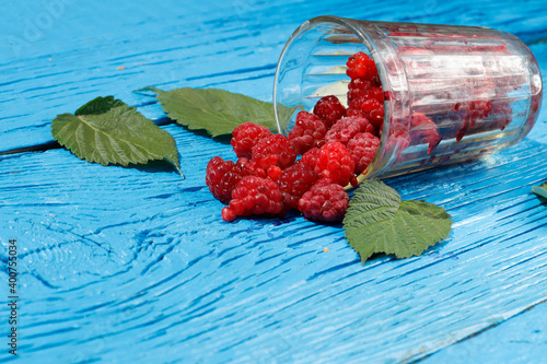 fresh raspberries in a glass glass with leaves on an old wooden background