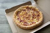 Hawaiian Pizza with bacon , cheese and pineapple on cardboard box.Restaurant promotion concept.