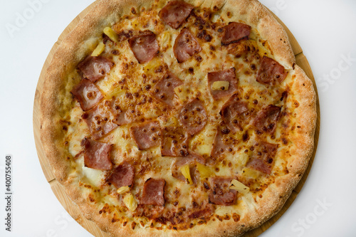 Tasty hawaiian pizza top view with cheese ,crispy bacon and pineapple on wooden pizza board and white background. photo