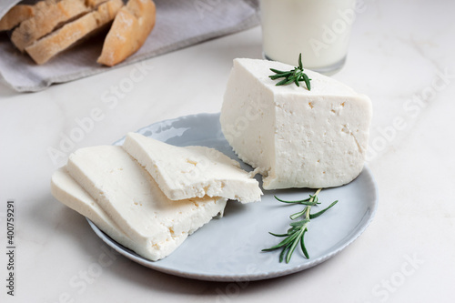 Adyghe cheese is cut into pieces on a gray plate. Soft goat cheese photo