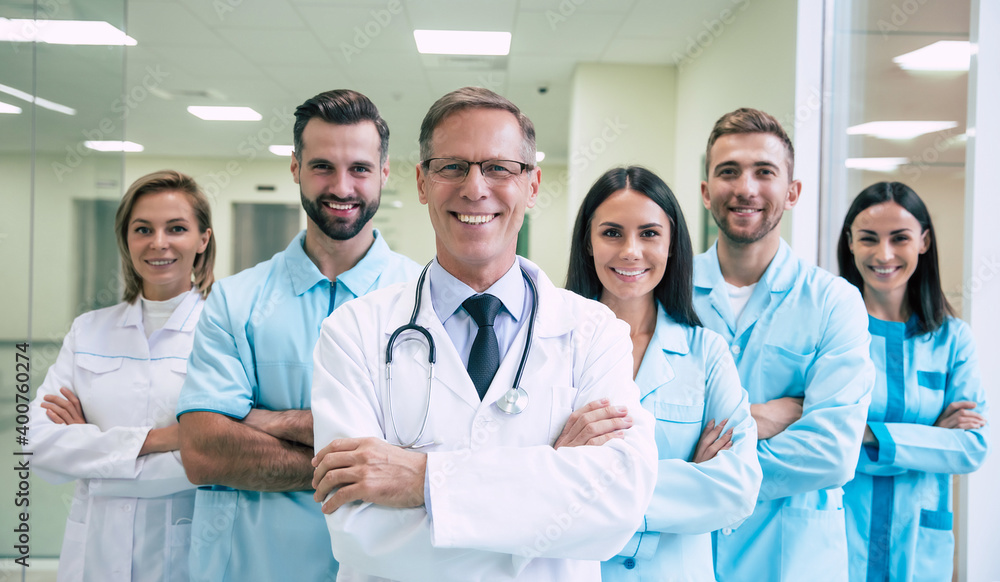 Happy team of successful and confident modern medical doctors are posing and looking on the camera at the hospital corridor Happy team of successful and confident modern medical doctors are posing and looking on the camera at the hospital corridor