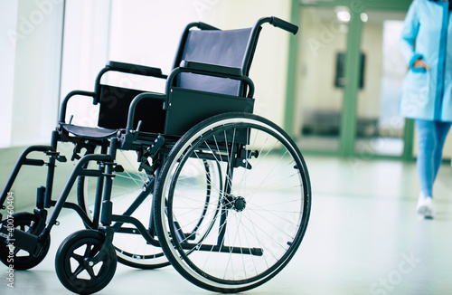Close up photo of an empty wheelchair in the hospital corridor with a woman doctor in the background
