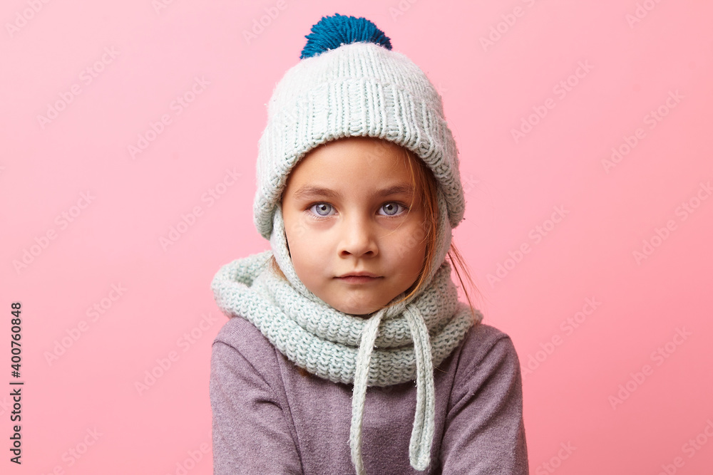 Close up studio portrait of cute frozen little girl with a big eyes wearing knit winter clothes over pink background. Close up studio portrait of cute frozen little girl with a big eyes wearing knit winter clothes over pink background.