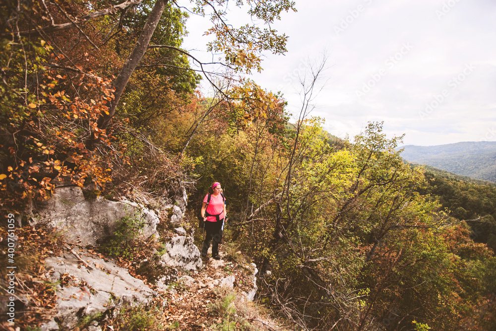 Hiking Woman with backpack. Walking on forest trail on autumn day. Nature lifestyle.