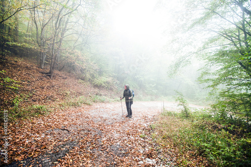 Hike Woman walking on foggy autumn day through misty forest. Healthy lifestyle. © mitarart