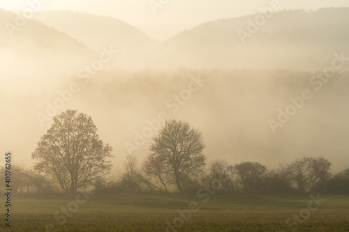 Scenic view of thick fog rolling over valley at sunrise. Beautiful autumnal landscape background