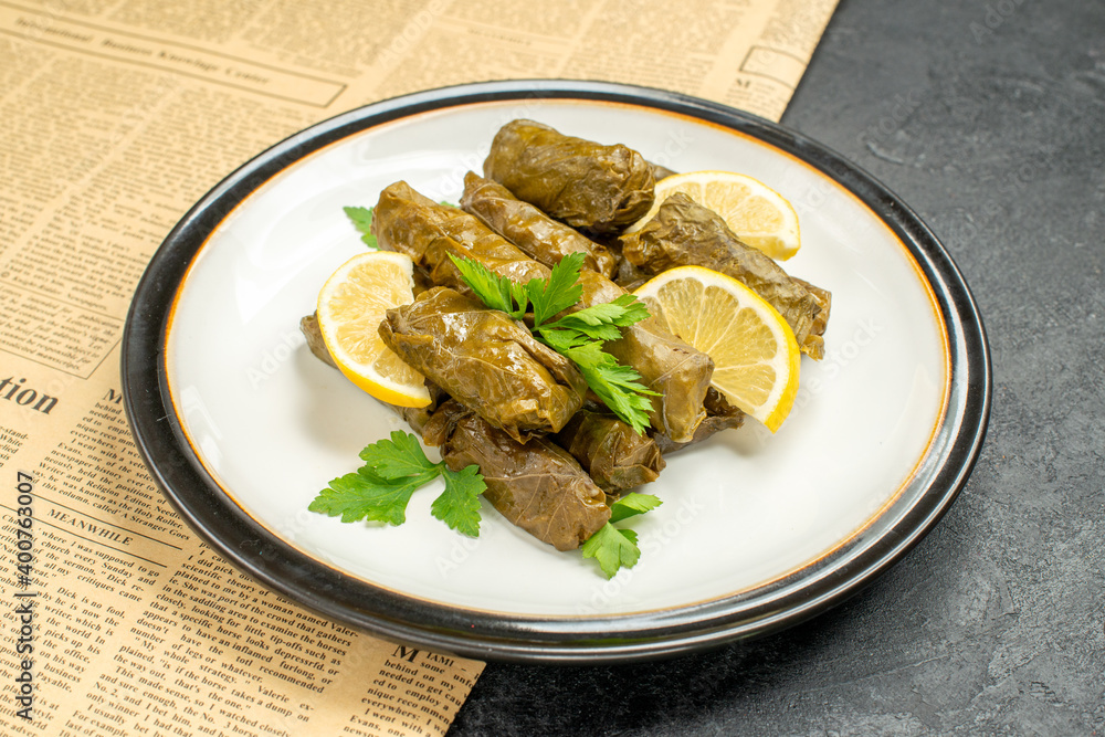 bottom view stuffed grape leaves on white plate traditional azerbaijani dish a newspaper on dark background bottom view stuffed grape leaves on white plate traditional azerbaijani dish a newspaper on dark background