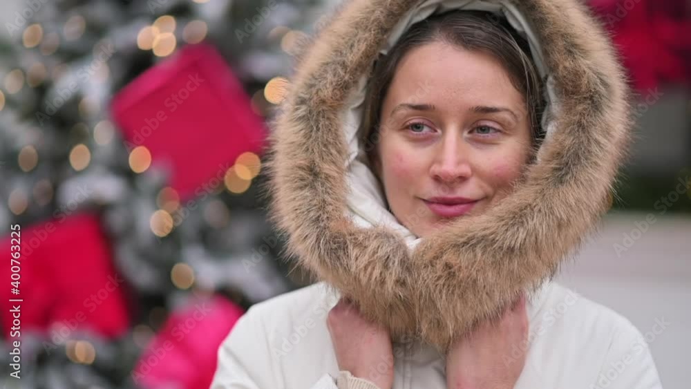 Happy woman wearing white winter coat at the christmas market with decorations smiling Happy woman wearing white winter coat at the christmas market with decorations smiling