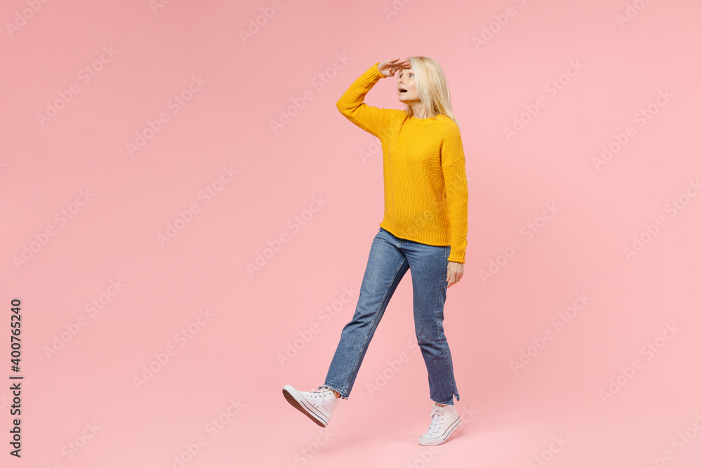 Full length side view of amazed elderly gray-haired blonde woman lady 40s 50s in yellow basic sweater hold hand at forehead looking far away distance isolated on pink color background studio portrait. Full length side view of amazed elderly gray-haired blonde woman lady 40s 50s in yellow basic sweater hold hand at forehead looking far away distance isolated on pink color background studio portrait.