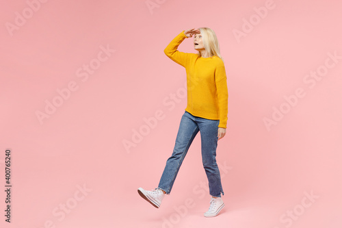 Full length side view of amazed elderly gray-haired blonde woman lady 40s 50s in yellow basic sweater hold hand at forehead looking far away distance isolated on pink color background studio portrait. photo